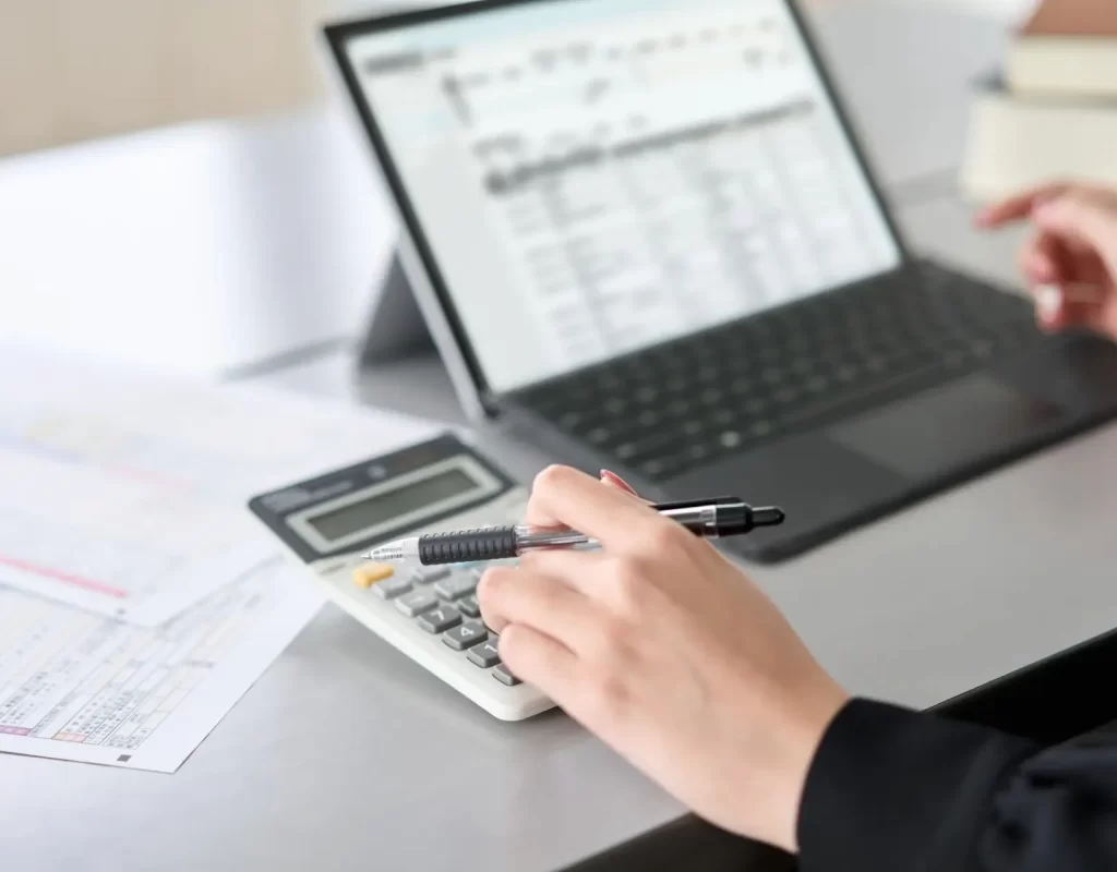Asian woman using accounting software and calculator